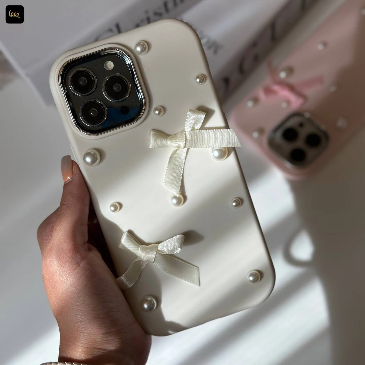 قاب آیفون چُبی پاپیونی Chubby Bowtie با روبان و مروارید برجسته در دو رنگ سفید صدفی و صورتی ملایم